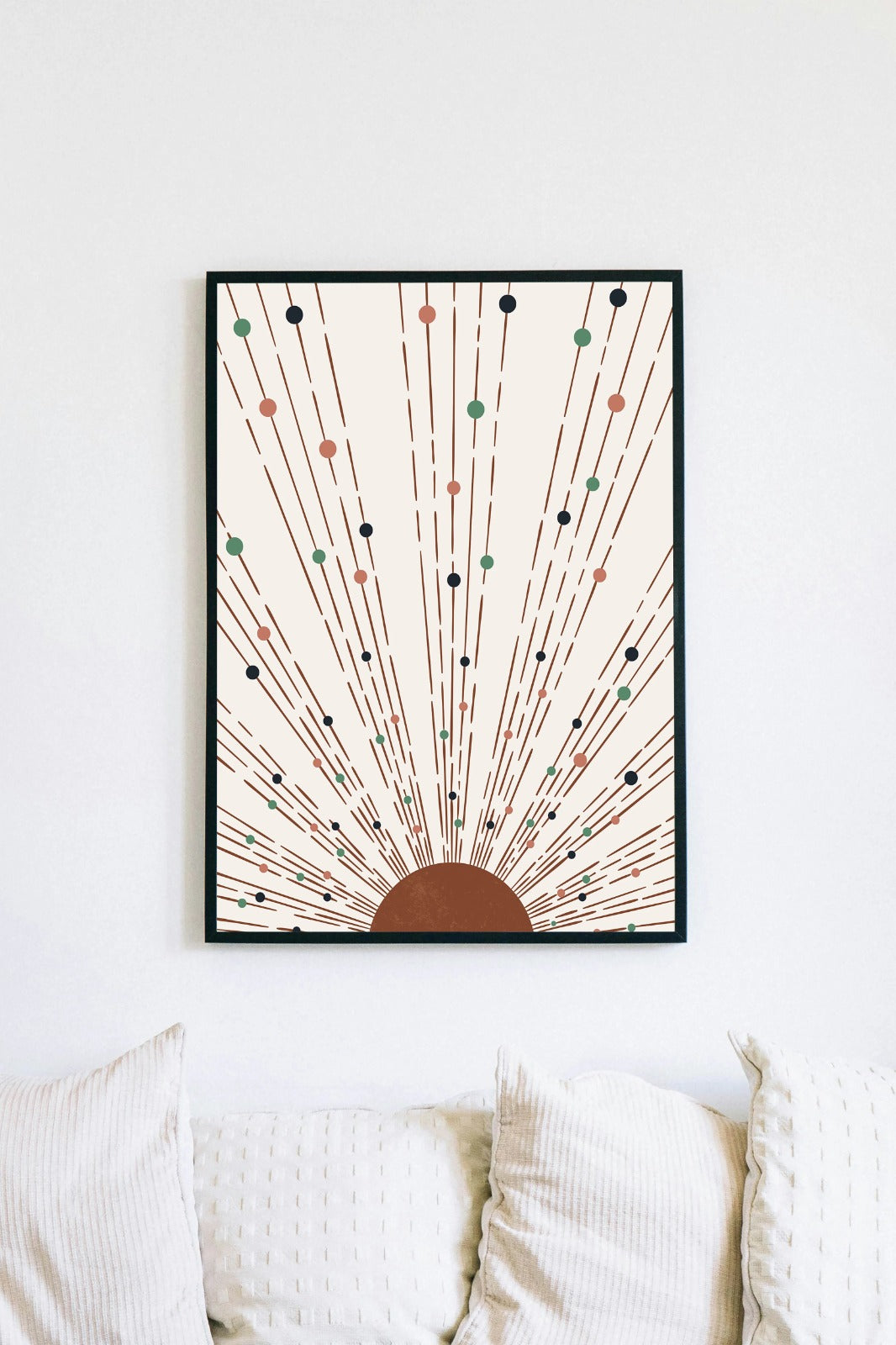 a framed artwork hanging on a wall above a white couch with pillows.